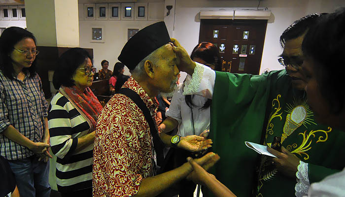 Salah seorang pasien diberi sakramen peminyaan oleh salah seorang Romo Gereja Santa Maria Tak Bercela. (foto : Erfan Hazransyah/ngopibareng.id)