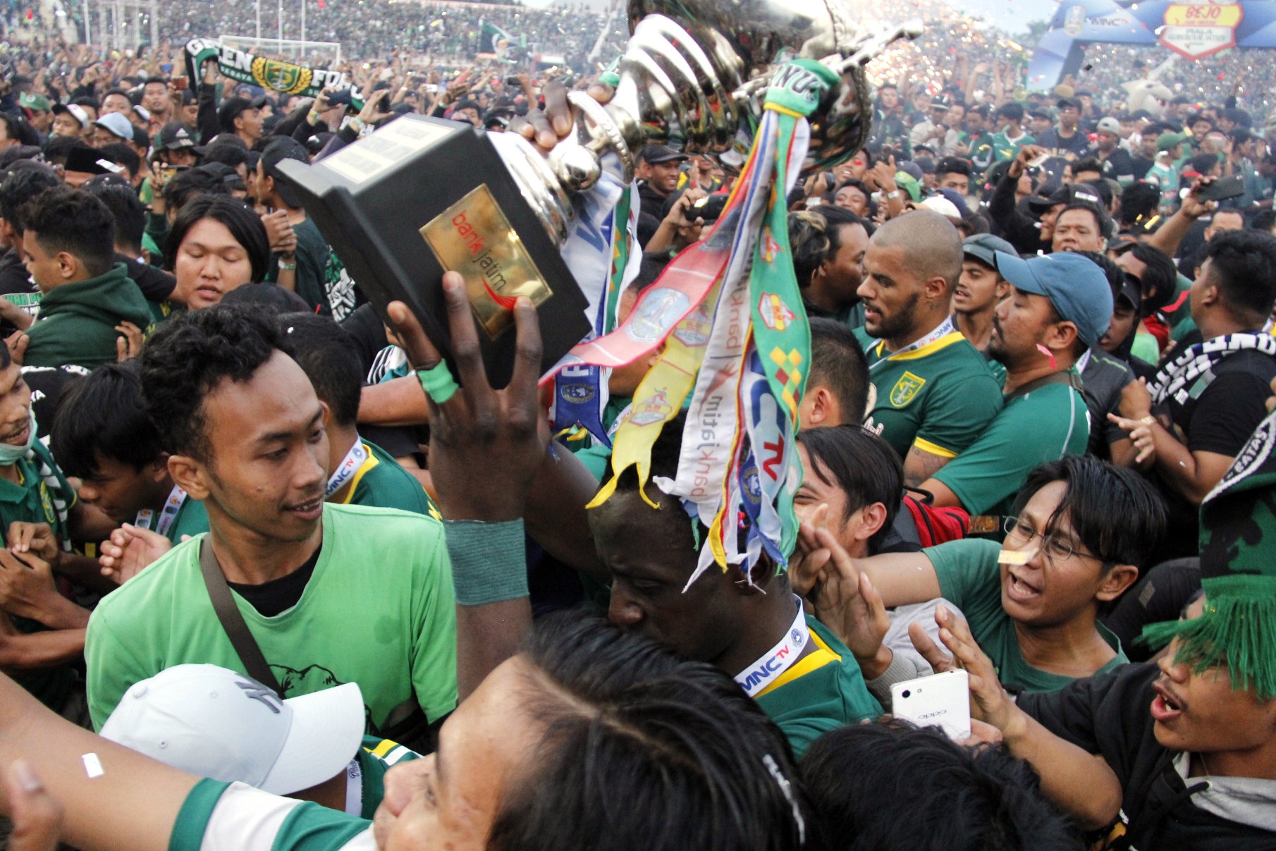 Pemain Persebaya, Makan Konate membawa piala menjadi serbuan Bonek Mania yang ingin berfoto dan memegang Piala Bergilir Gubernur Jatim usai laga final Piala Gubernur Jatim 2020 di Stadion Gelora Delta, Sidoarjo, Kamis 20 Februari 2020. (Foto: Fariz Yarbo/Ngopibareng.id)