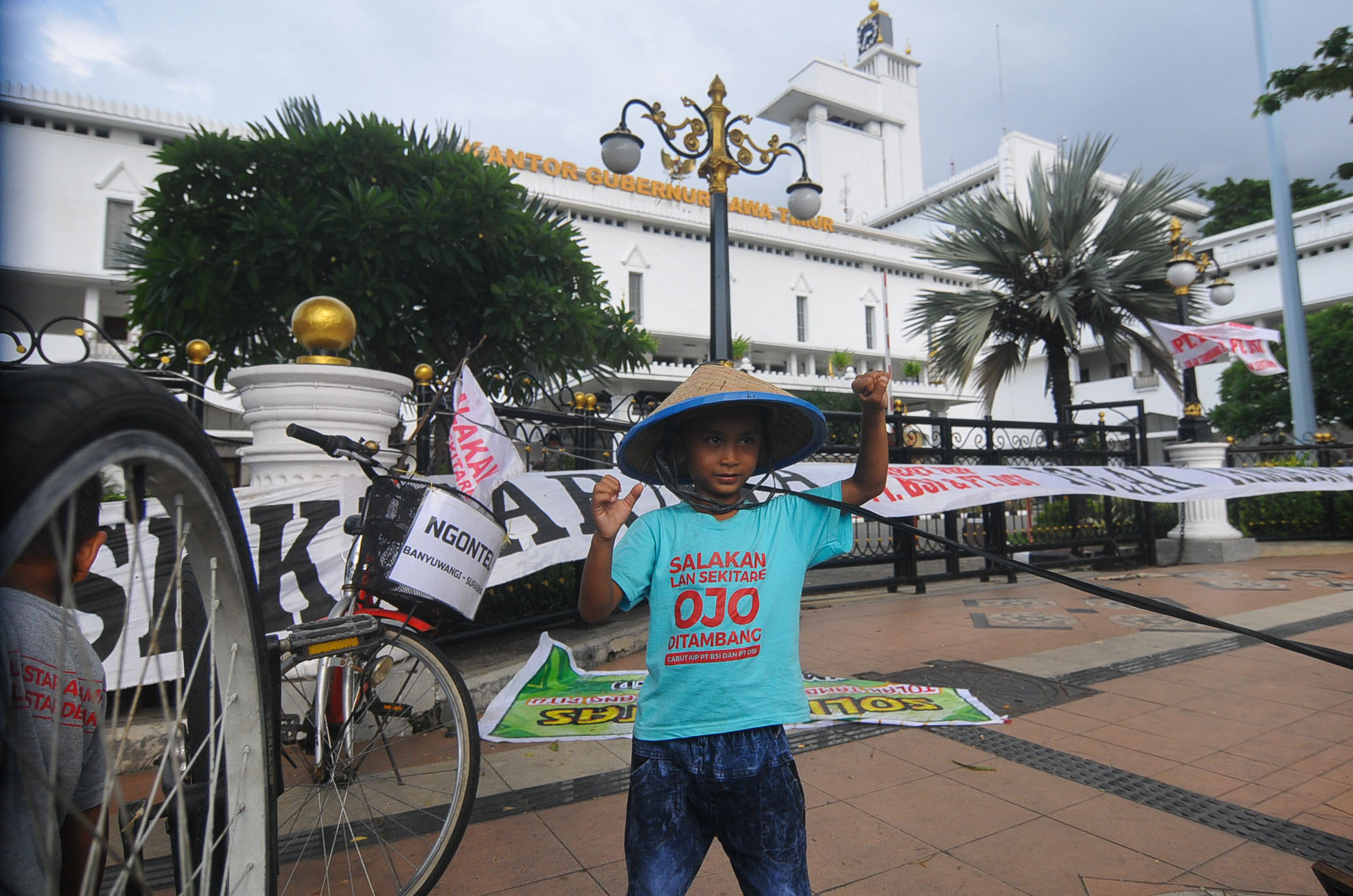 Seorang anak dari warga Tumpang Pitu Banyuwangi, berpose di depan kantor Gubernur Jawa Timur. (foto : Erfan Hazransyah/ngopibareng.id)