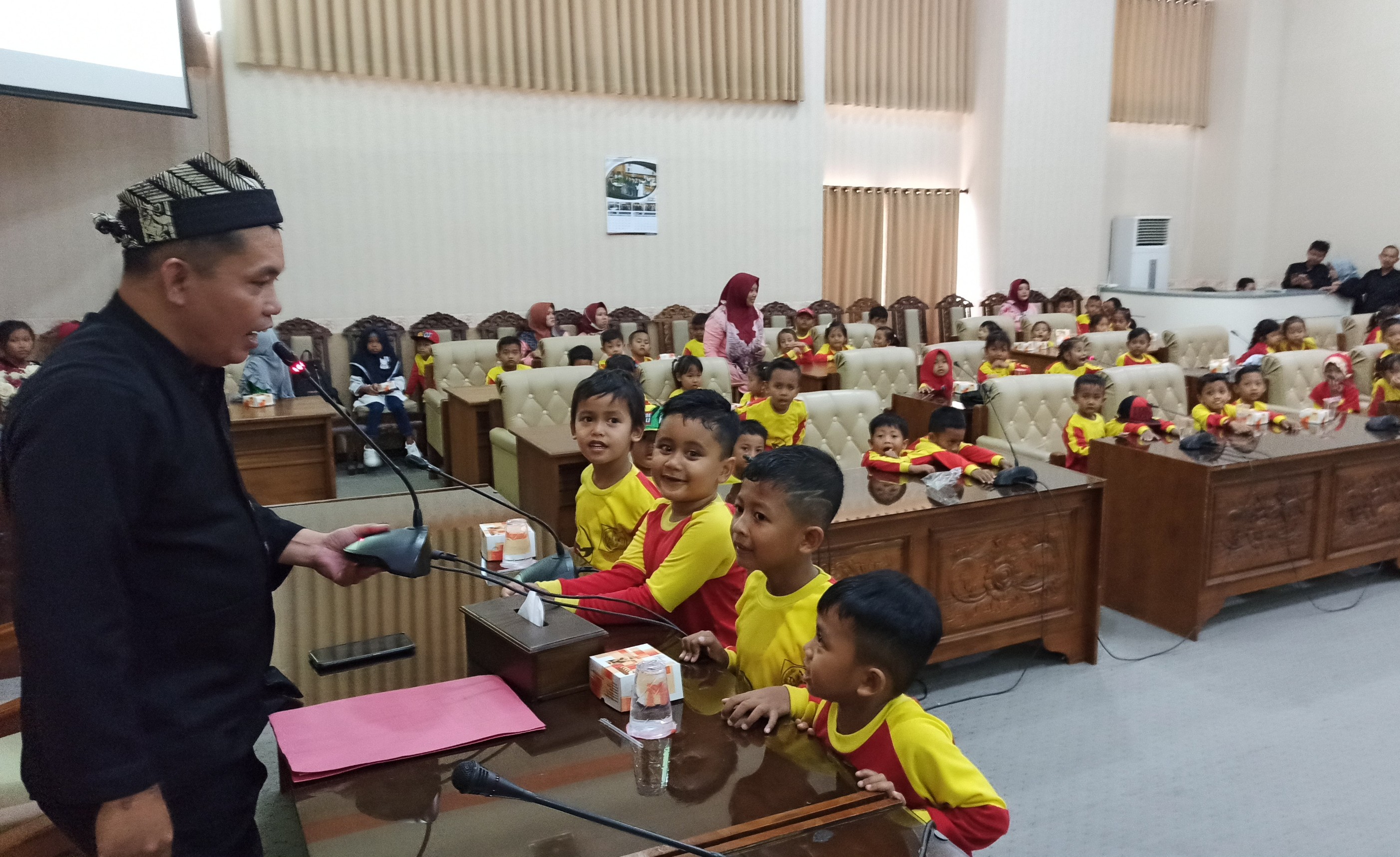 Kasubag Keprotokolan dan Tata Usaha Sekretariat DPRD Banyuwangi, Imam Basuki berinteraksi dengan murid TK Yang berkunjung ke DPRD Banyuwangi. (Foto: Muh. Hujaini/Ngopibareng.id)