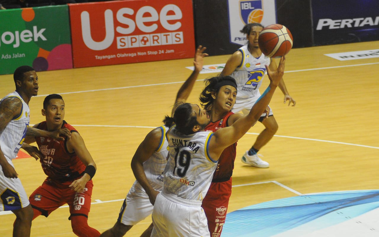 Pemain Louvre Surabaya, Dimas Muharri berebut bola dengan pemain Prawira Bandung, M Reza Fardani Guntara dalam laga seri enam Indonesian Basketball League (IBL) 2020 di DBL Arena, Surabaya, Jumat 6 Maret 2020. (Foto: Erfan Hazransyah/Ngopibareng.id)