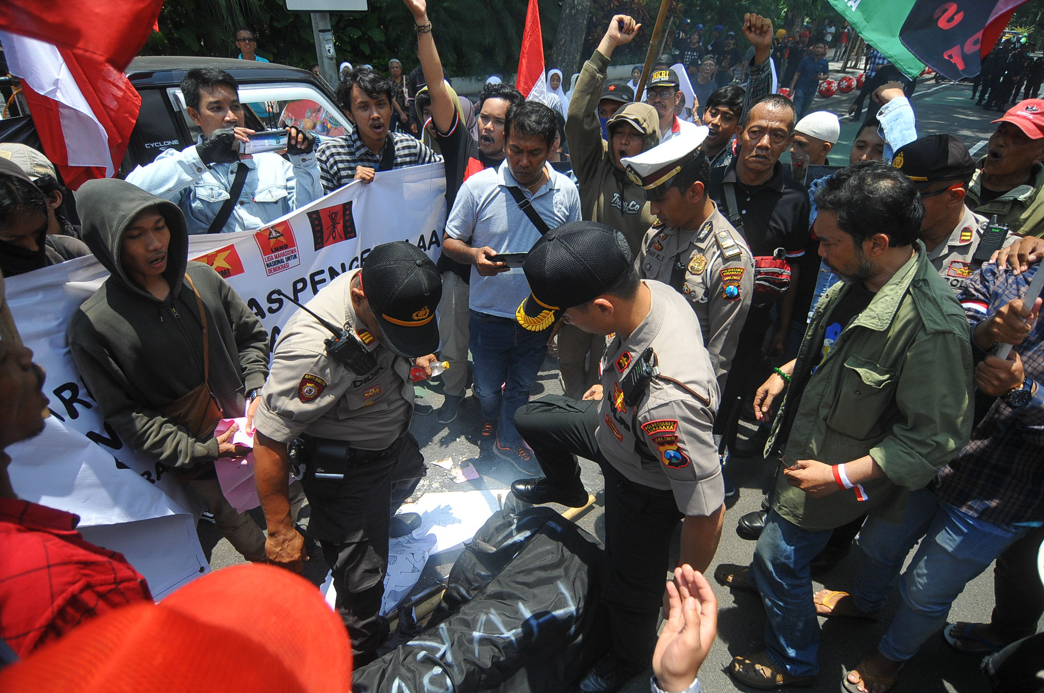 Petugas kepolisiaan berusaha mematikan api yang sengaja disulut olah massa aksi. (Foto: Erfan Hazransyah/Ngopibareng.id)