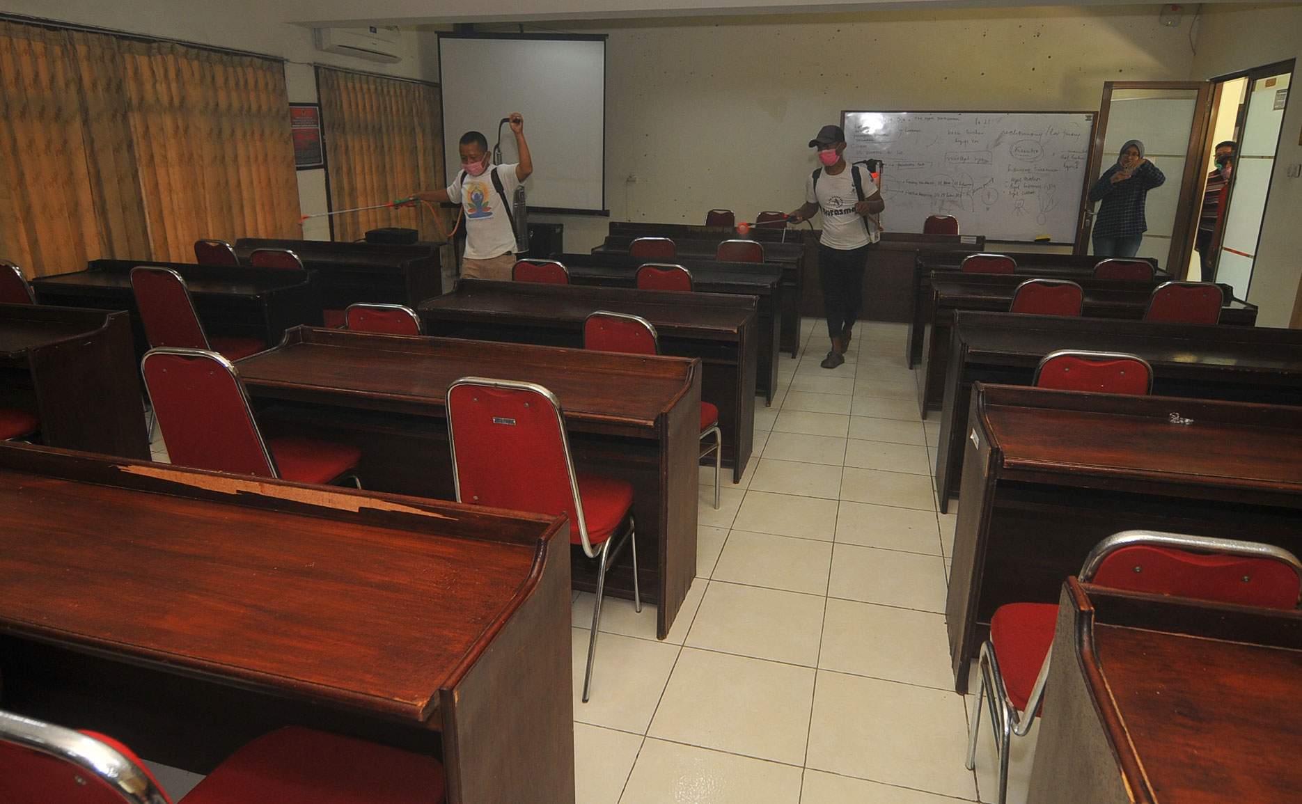 Petugas dari internal kampus Untag menyemprot cairan disinfektan disalah satu ruang kulah. (Foto: Erfan Hazransyah/Ngopibareng.id)