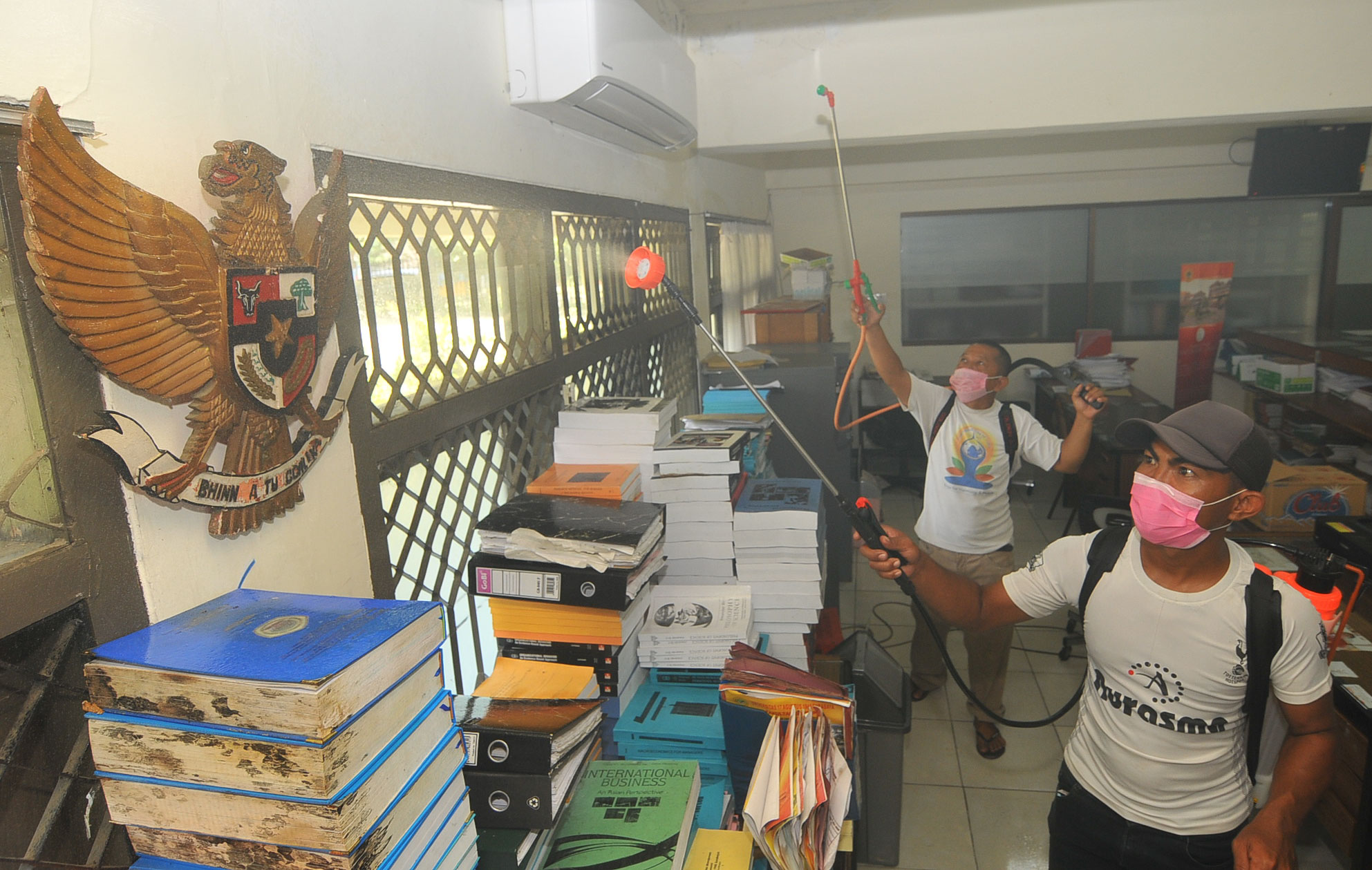 Petugas menyemprot cairan disinfektan disalah satu ruang administrasi kampus Untag. (Foto: Erfan Hazransyah/Ngopibareng.id)