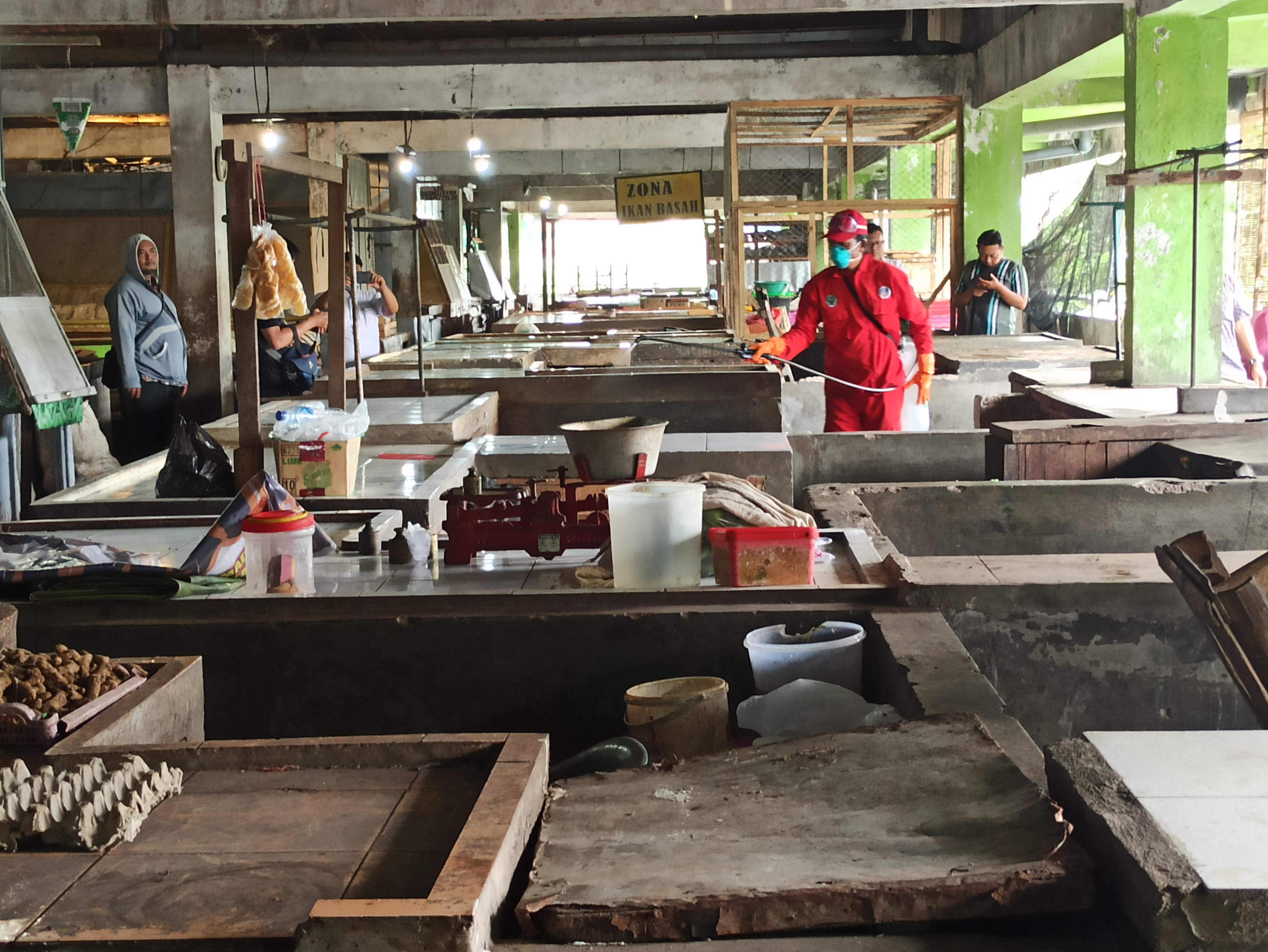 Petugas Dinkes melakukan penyemprotan disinfektan sejumlah lapak pedagang. (Foto: Fendi Plesmana/Ngopibareng.id)