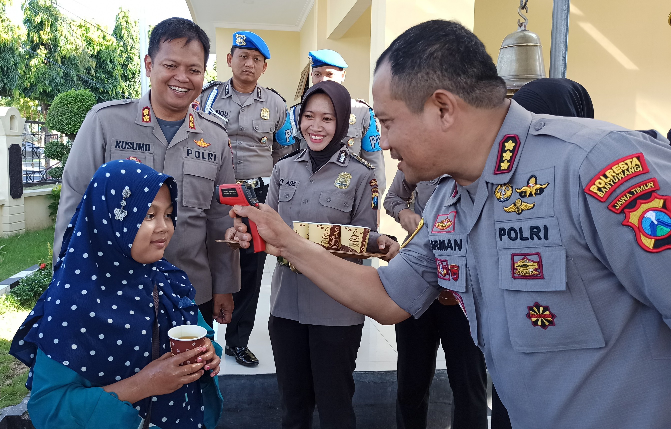 Kapolresta Banyuwangi Kombespol Arman Asmara Syarifuddin mengecek suhu tubuh salah seorang warga yang datang ke Polresta Banyuwangi. (Foto: Muh. Hujaini/Ngopibareng.id)