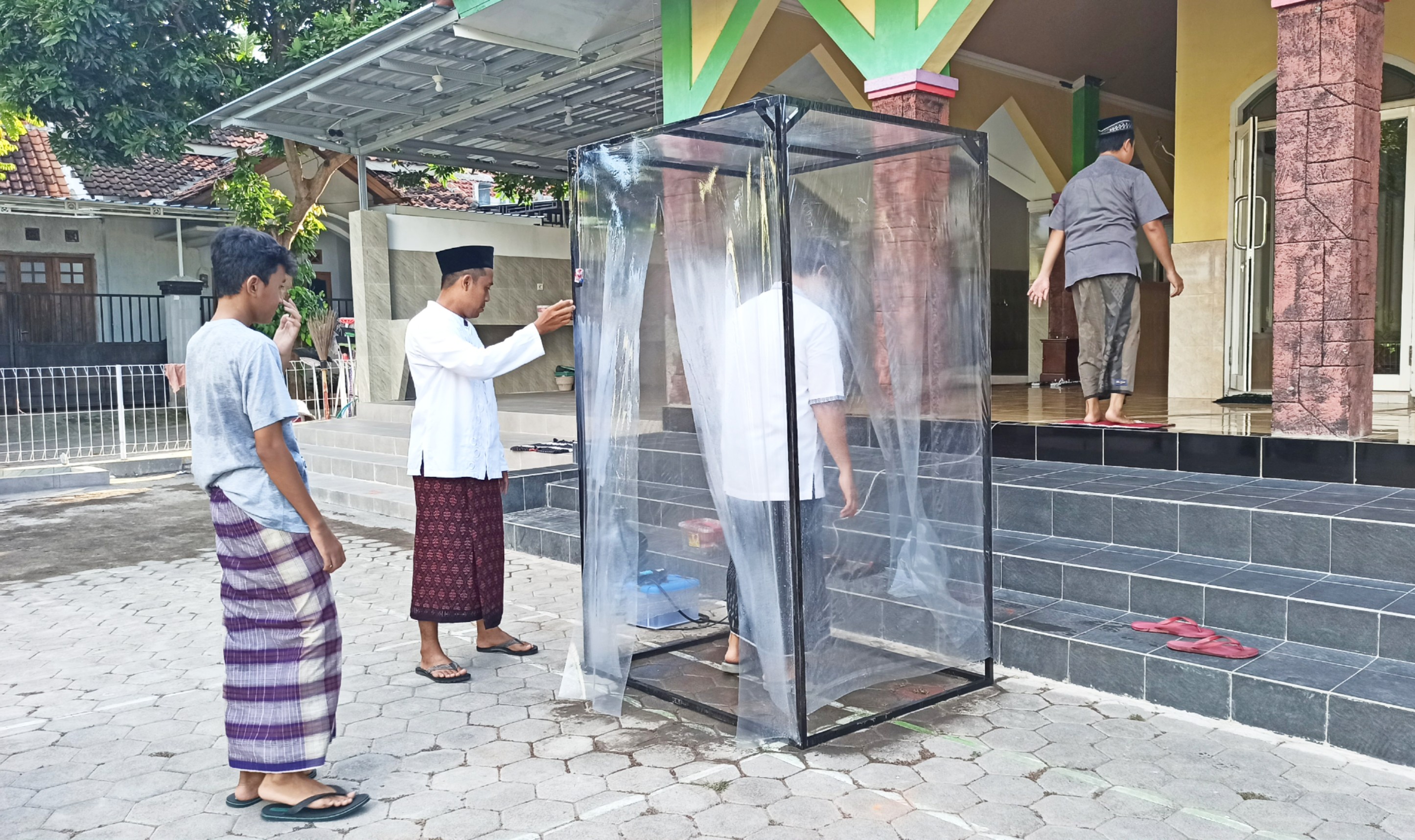 Jemaah Masjid Al Hidayad harus memasuki bilik sterilisasi sebelum masuk ke masjid. (Foto: Muh Hujaini/Ngopibareng.id)