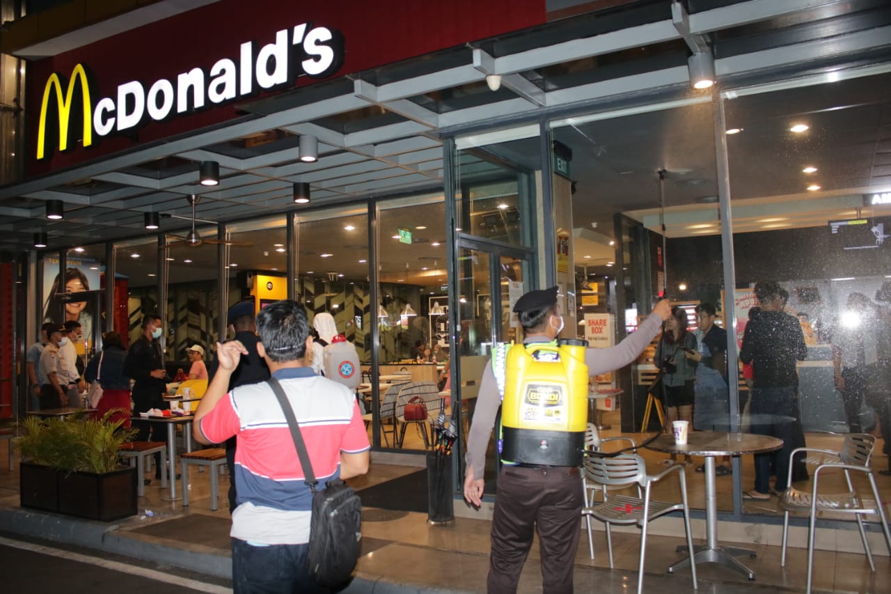 Petugas kepolisian saat mengimbau pengunjung di salah satu restoran cepat saji di daerah Surabaya Barat. (Foto: Istimewa0