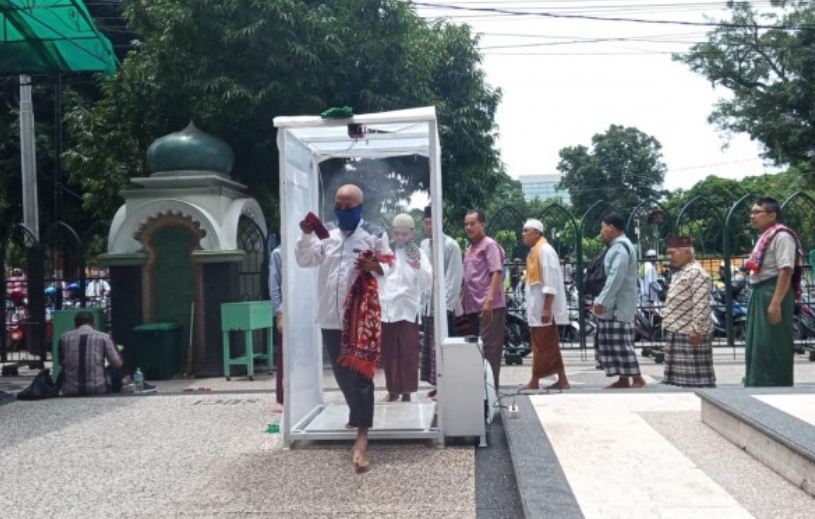 Jemaah shalat Jumat di Masjid Jami'Kota Malang saat disemprotkan desinfektan (Foto: Lalu Theo/Ngopibareng.id)