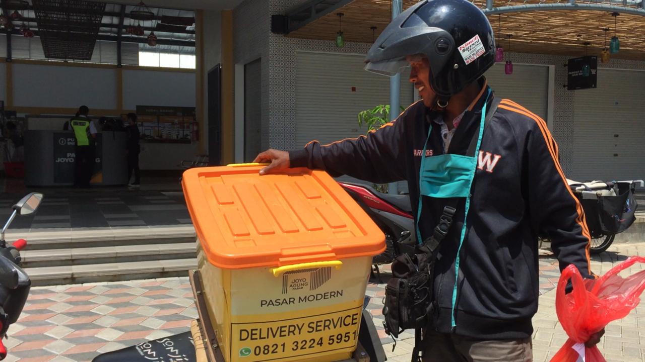 Petugas mengantar barang belanjaan pesanan pembeli di Pasar Joyo Agung, Kota Malang. (Foto: Lalu Theo/Ngopibareng.id)