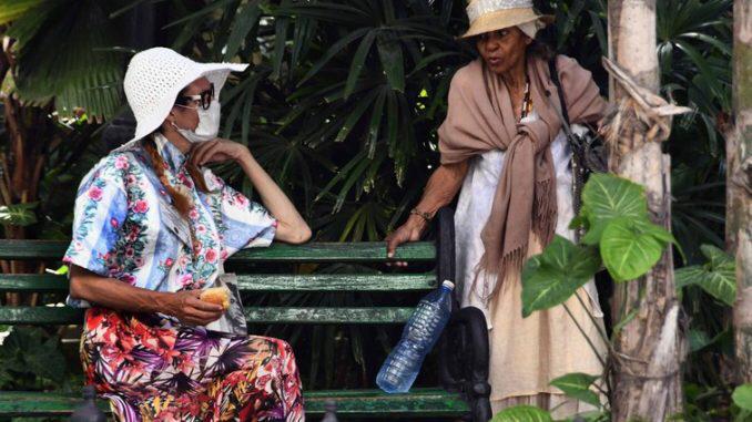 Seorang wanita yang mengenakan masker wajah berbicara kepada temannya di sebuah jalan di Havana, Kuba, 17 Maret 2020. (Foto: Joaquin Hernandez/Xinhua/PA)