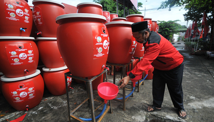 Salah seorang simpatisan PDIP menunjukkan tempat cuci tangan portebel yang sudah jadi dan siap pakai. (Foto: Erfan Hazransyah/Ngopibareng.id) 