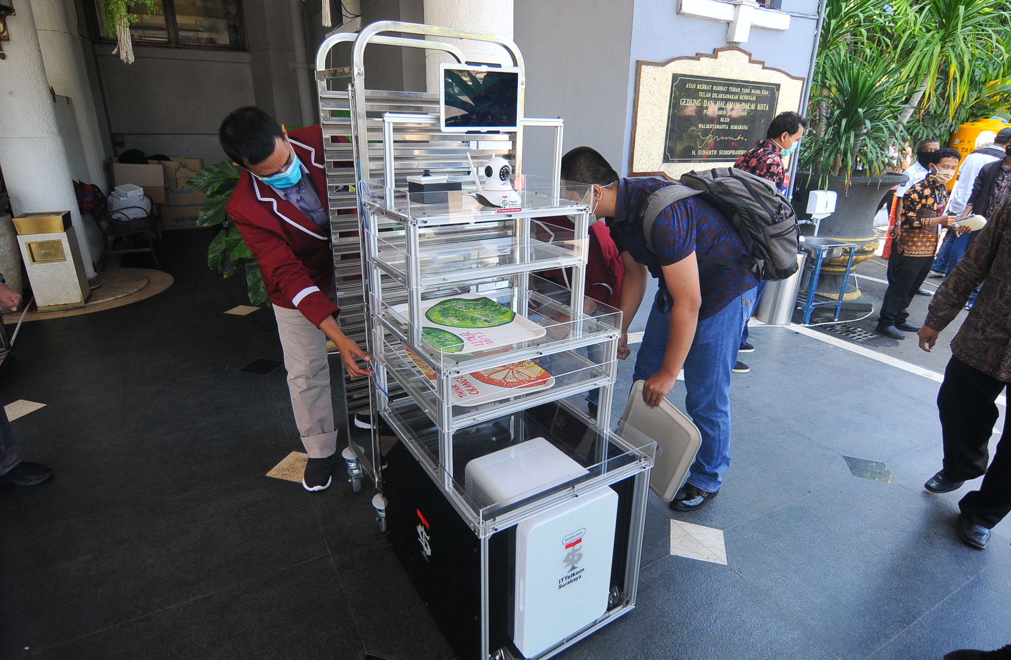Mahasiwa IT Telkom Surabaya mempersiapkan Robot Service di halaman Balai Kota Surabaya. (Foto: Erfan Haransyah/Ngopibareng.id)
