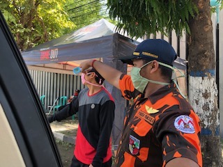 Anggota Ormas Kepemudaan periksa suhu badan penumpang mobil yang lewat.