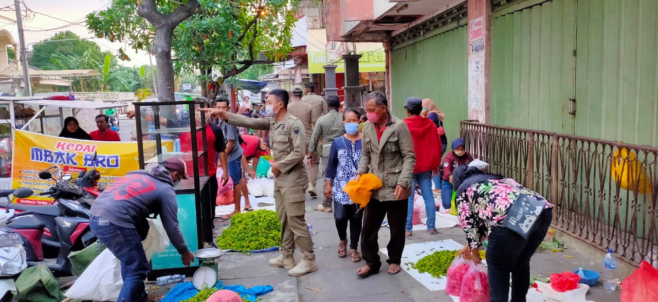 Petugas Satpol PP saat menata pedagang bunga musiman. (Foto: Fendhy Plesmana/Ngopibareng.id)