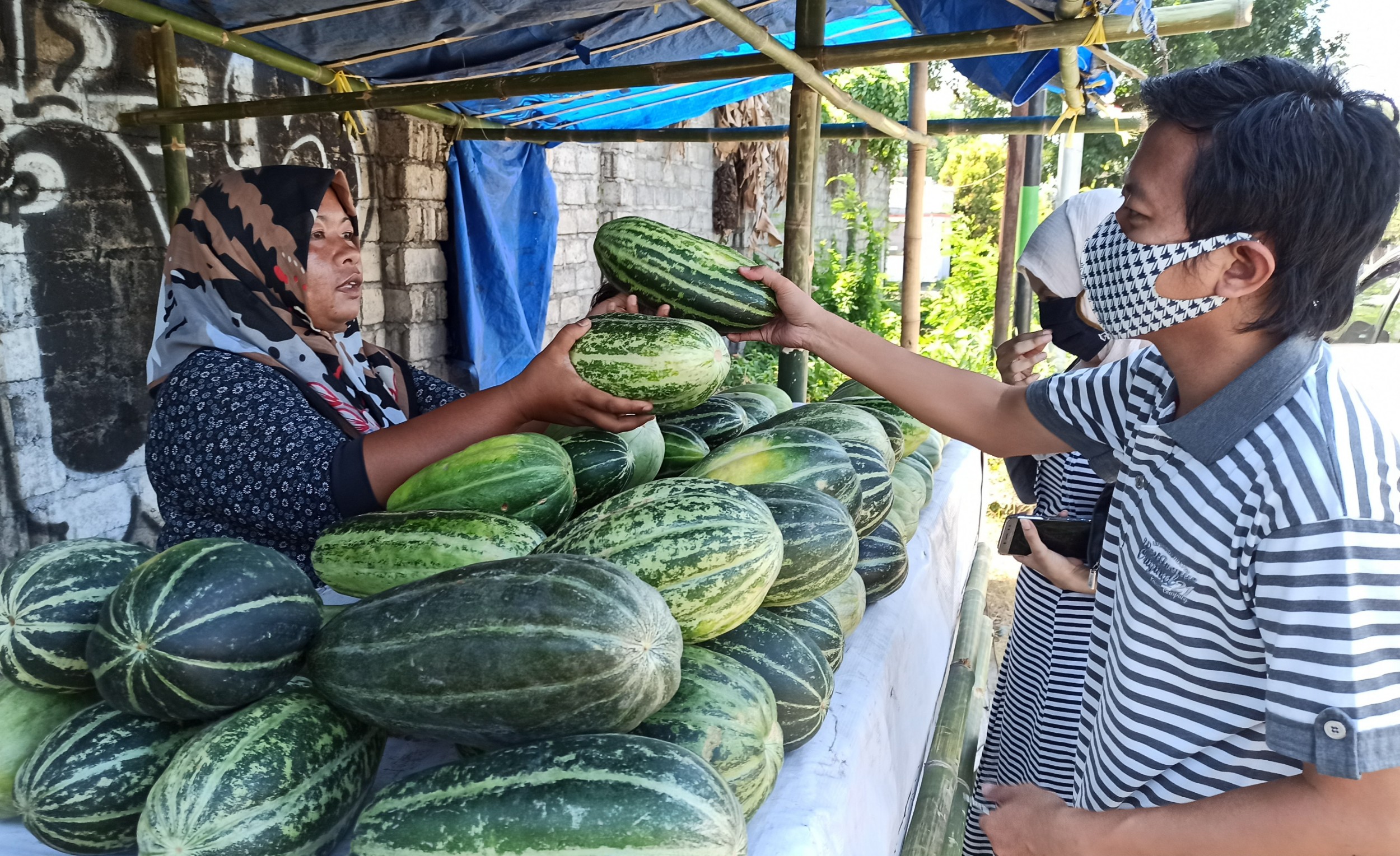 Mahardika sedang membeli buah Kerai di bidak milik Siti Nur Hadijah (foto: Hujaini/ngopibareng.id)