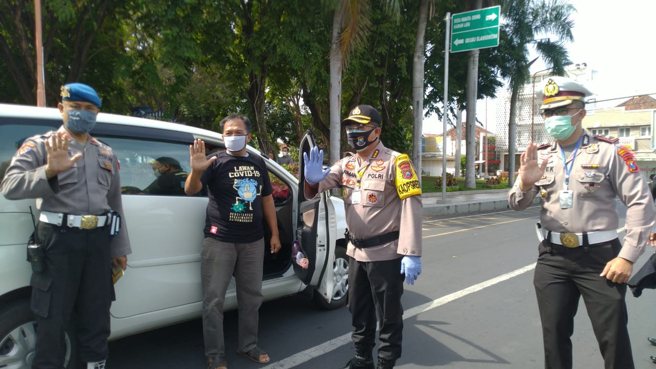 Kapolresta Banyuwangi Kombespol Arman Asmara Syarifuddin (dua dari kanan) berfoto bersama pengendara mobil yang mengenakan kaos lawan Covid-19. (Foto: Muh. Hujaini/Ngopibareng.id)