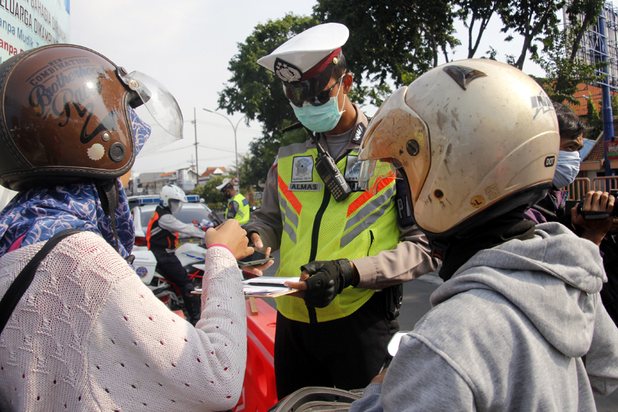 Petugas menindak pengendara yang melakukan pelanggaran di cek poin Waru, Sidoarjo, Sabtu 2 April 2020 sore. (Foto: Fariz Yarbo/Ngopibareng.id)