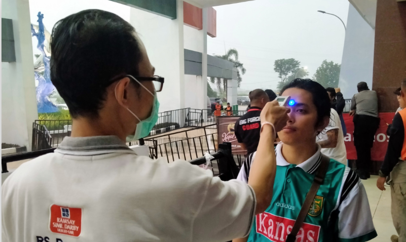 Tim kesehatan saat memeriksa suhu tubuh salah satu suporter di Stadion Gelora Bung Tomo (GBT), Surabaya, Jumat 13 Maret 2020. Stadion Gelora Bung Tomo Surabaya menjadi salah satu venue Piala Dunia U-20. (Foto: Fariz Yarbo/Ngopibareng.id)