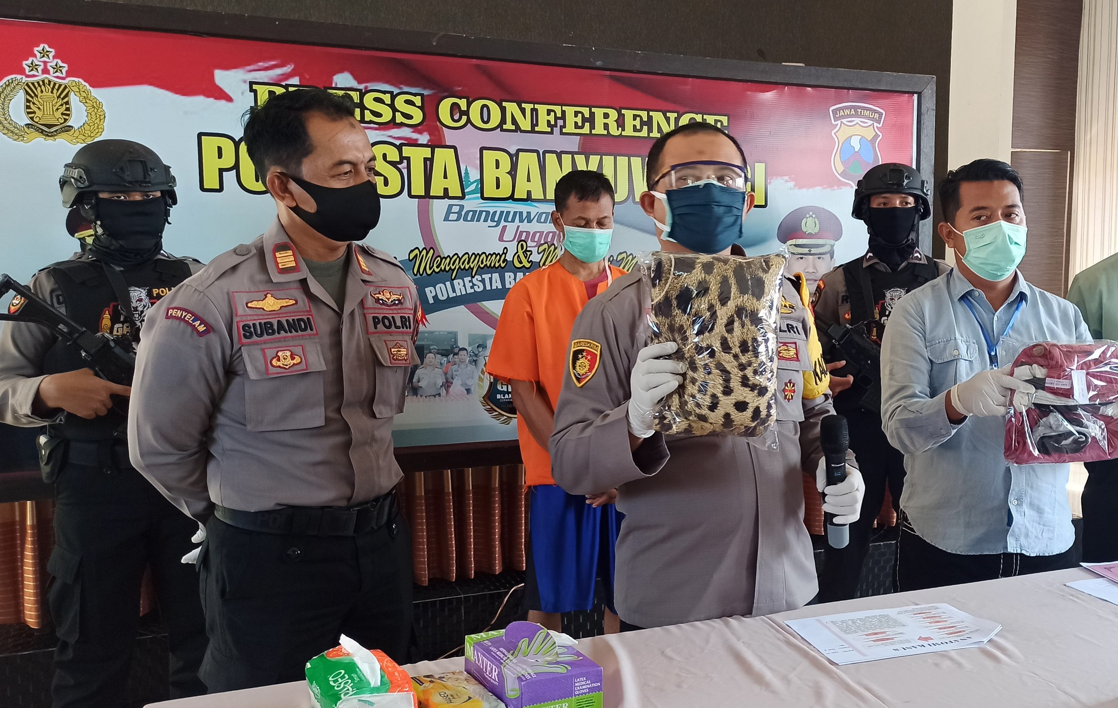 Kapolresta Banyuwangi Kombespol Arman Asmara Syarifuddin menunjukkan barangbukti kasus pencabulan. Tersangka SM (belakang) pria yang tega menyetubuhi anak tirinya. (Foto: Muh. Hujaini/Ngopibareng.id)