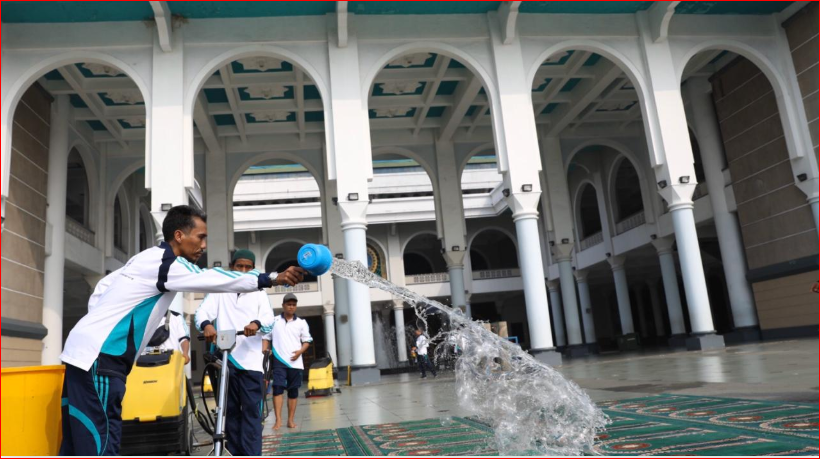 Petugas Masjid Nasional Al Akbar Surabaya, tengah membersihkan sajadah di dalam masjid. (Foto: Andhi Dwi/Ngopibareng.id)