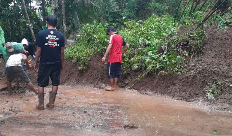 Petugas BPBD dibantu warga membersihkan material longsor di jalan Desa Keluncing, Kecamatan Licin, Banyuwangi. (Foto: Muh. Hujaini/Ngopibareng.id)