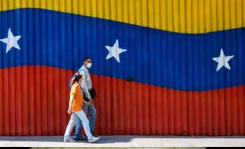 Dua orang warga melintas di sudut ibukota Caracas, Venezuela di tengah pandemi corona. (Foto:Reuters)