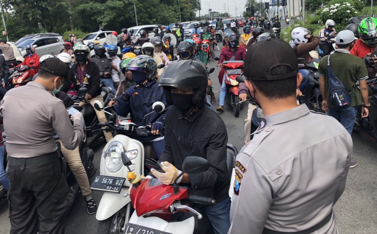 Petugas check point Waru, Surabaya, sedang memeriksa KTP pengendara yang melintas (Andik/Ngopibareng.id)