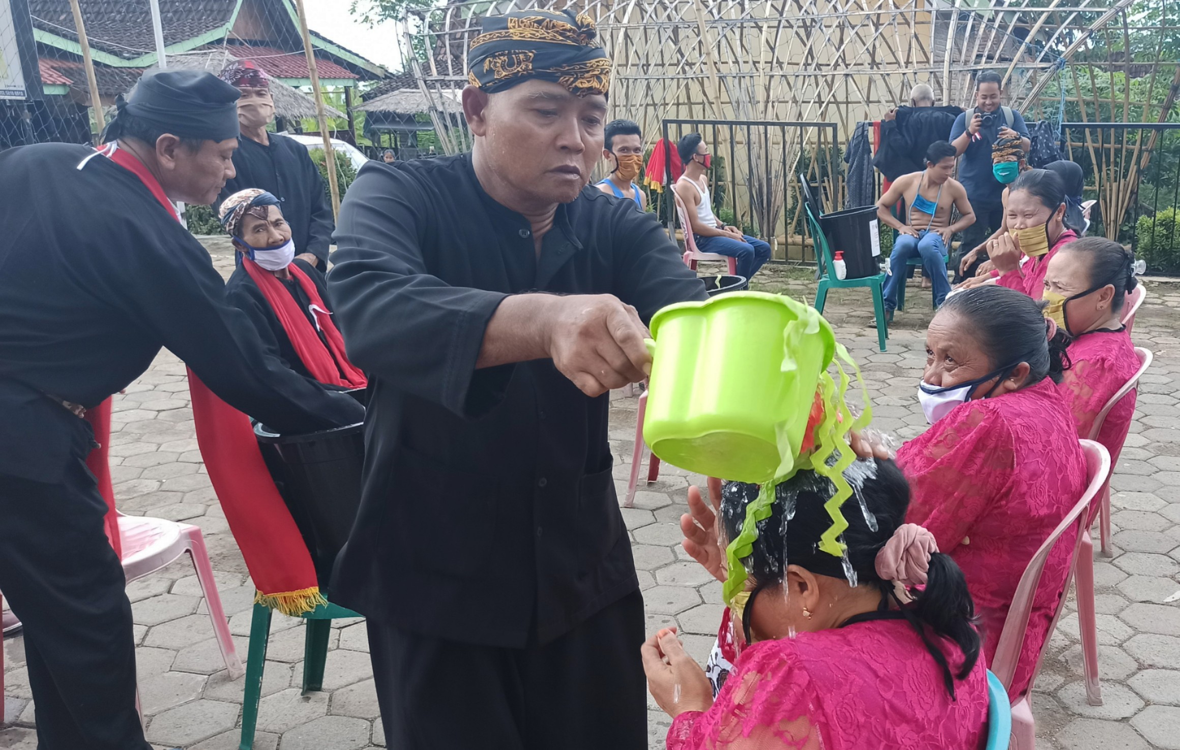 Pawang Seblang, Akwan menyiramkan air bunga kepada warga adat. (Foto: Muh. Hujaini/Ngopibareng.id)