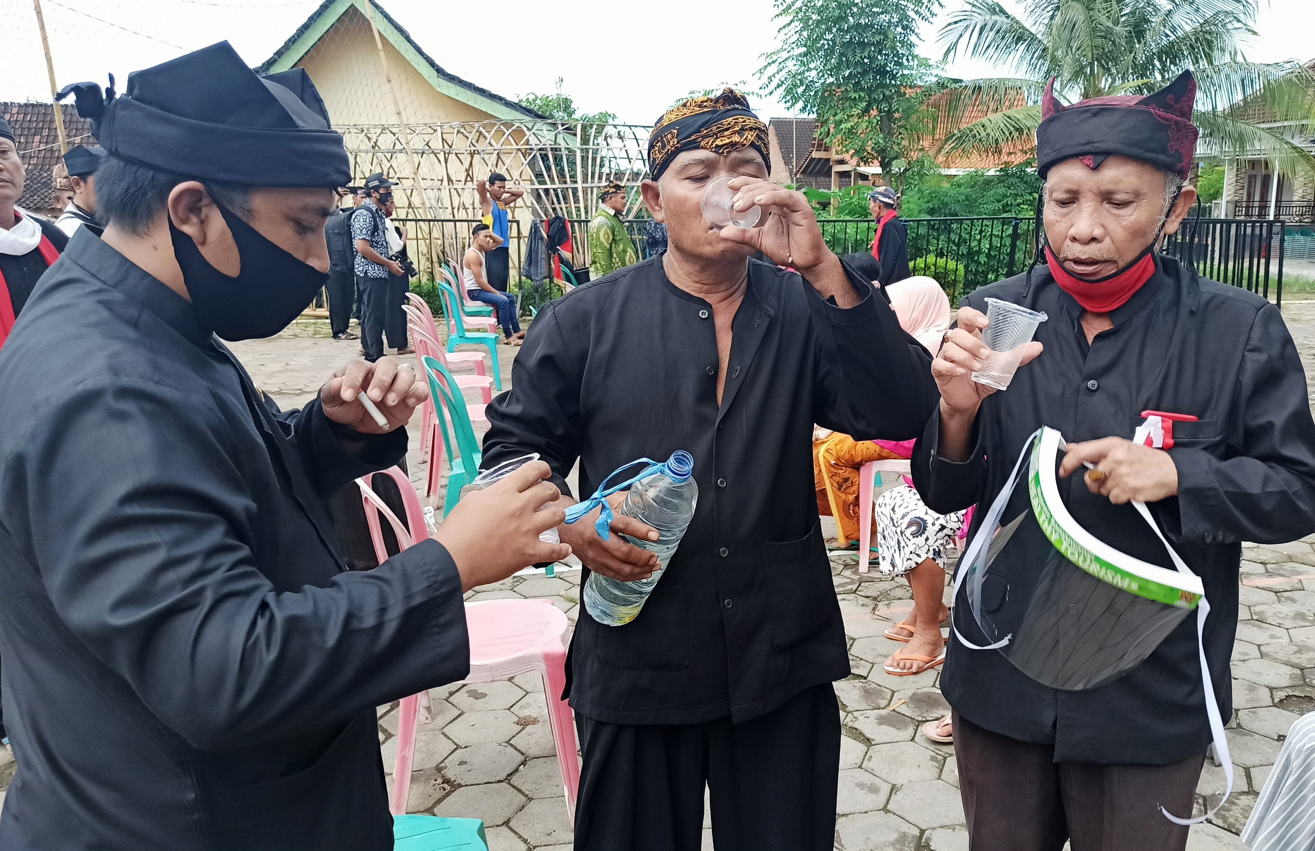 Kepala Desa Olehsari, Joko Mukhlis (kiri), Pawang Seblang, Akwan (tengah) dan Ketua Panitia Eko Sukartono meminum air untuk menghilangkan pandemi Covid-19 (Foto: Muh. Hujaini/Ngopibareng.id)