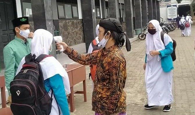 Santri yang kembali ke Pesantren Genggong, Kabupaten Probolinggo diperiksa dengan thermo gun. (foto: Ikhsan Mahmudi/ngopibareng.id)