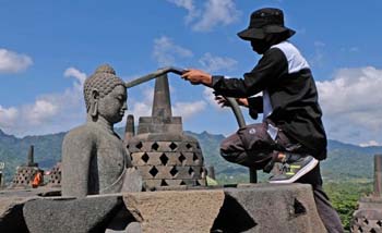 Petugas Balai Konservasi Borobudur (BKB) hari Senin 22 Juni menyemprotkan air untuk membersihkan debu akibat erupsi Gunung Merapi. (Foto:Antara) 