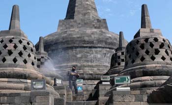 Petugas Balai Konservasi Borobudur (BKB) hari Senin 22 Juni menyemprotkan air untuk membersihkan debu akibat erupsi Gunung Merapi. (Foto:Antara) 