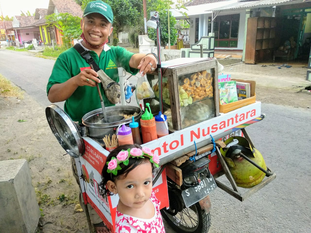Cak Pan (bertopi hijau) saat melayani pembeli pentol, Inara Azalea. (Foto: M.Rizqi/Ngopibareng.id)