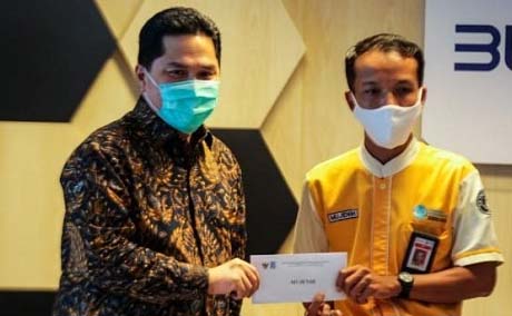 Menteri BUMN Erick Thohir memberi hadiah pada Mujenih, salah satu petugas kebersihan KRL. (Foto:Antara)