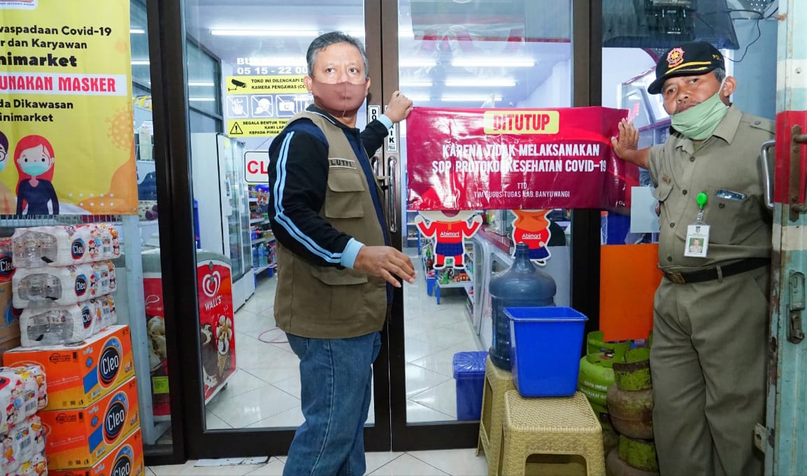 Petugas menyegel salah satu minimarket yang tidak menerapkan protokol kesehatan Covid-19. (Foto: Istimewa) 