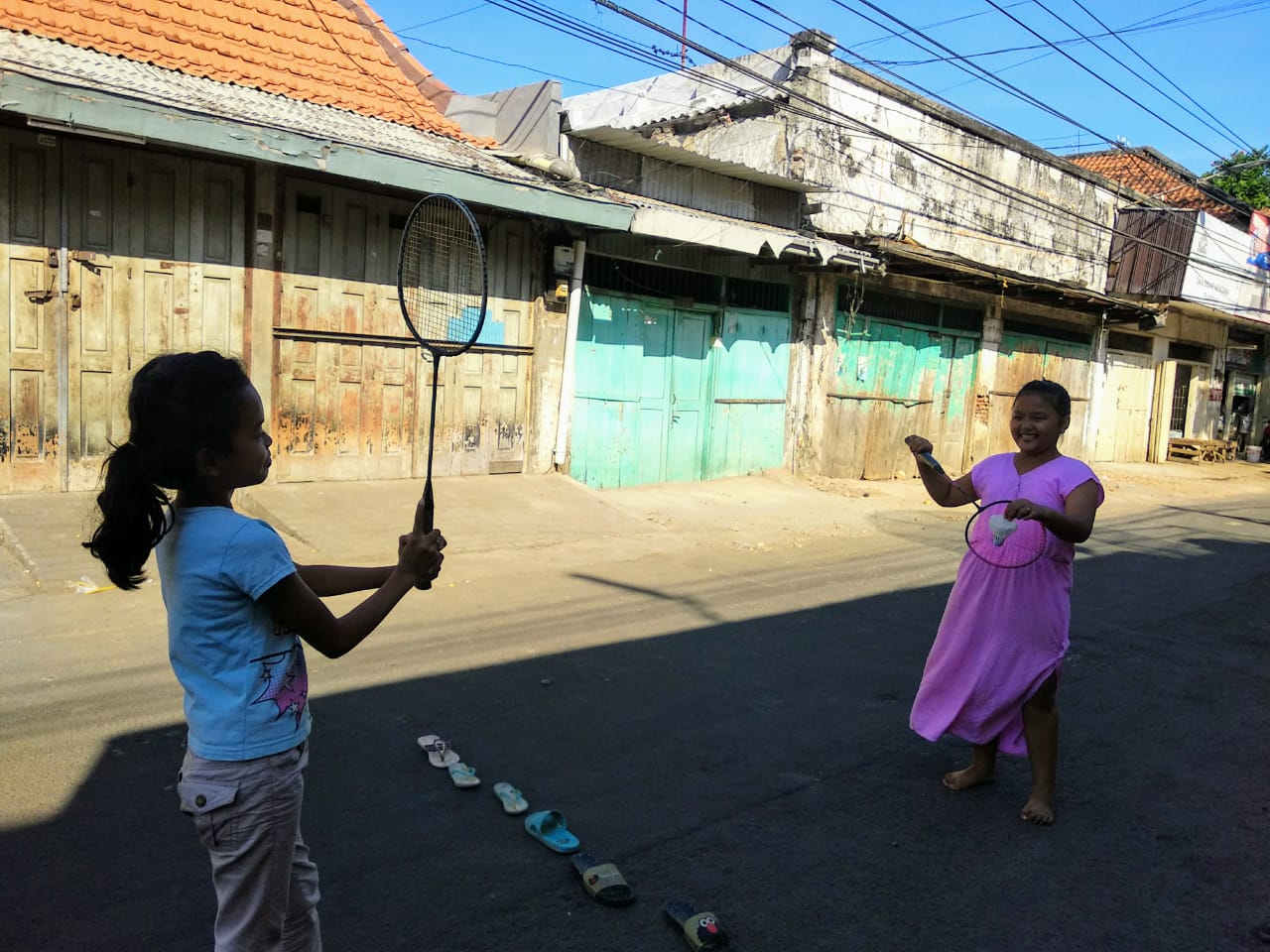 Dua anak perempuan tampak asyik bermain badminton di jalanan sekitar Pasar Keputran yang sepi pada pukul 15.00 WIB. Sayangnya, keduanya tidak menggunakan masker. (Foto: M.Rizqi/Ngopibareng.id)
