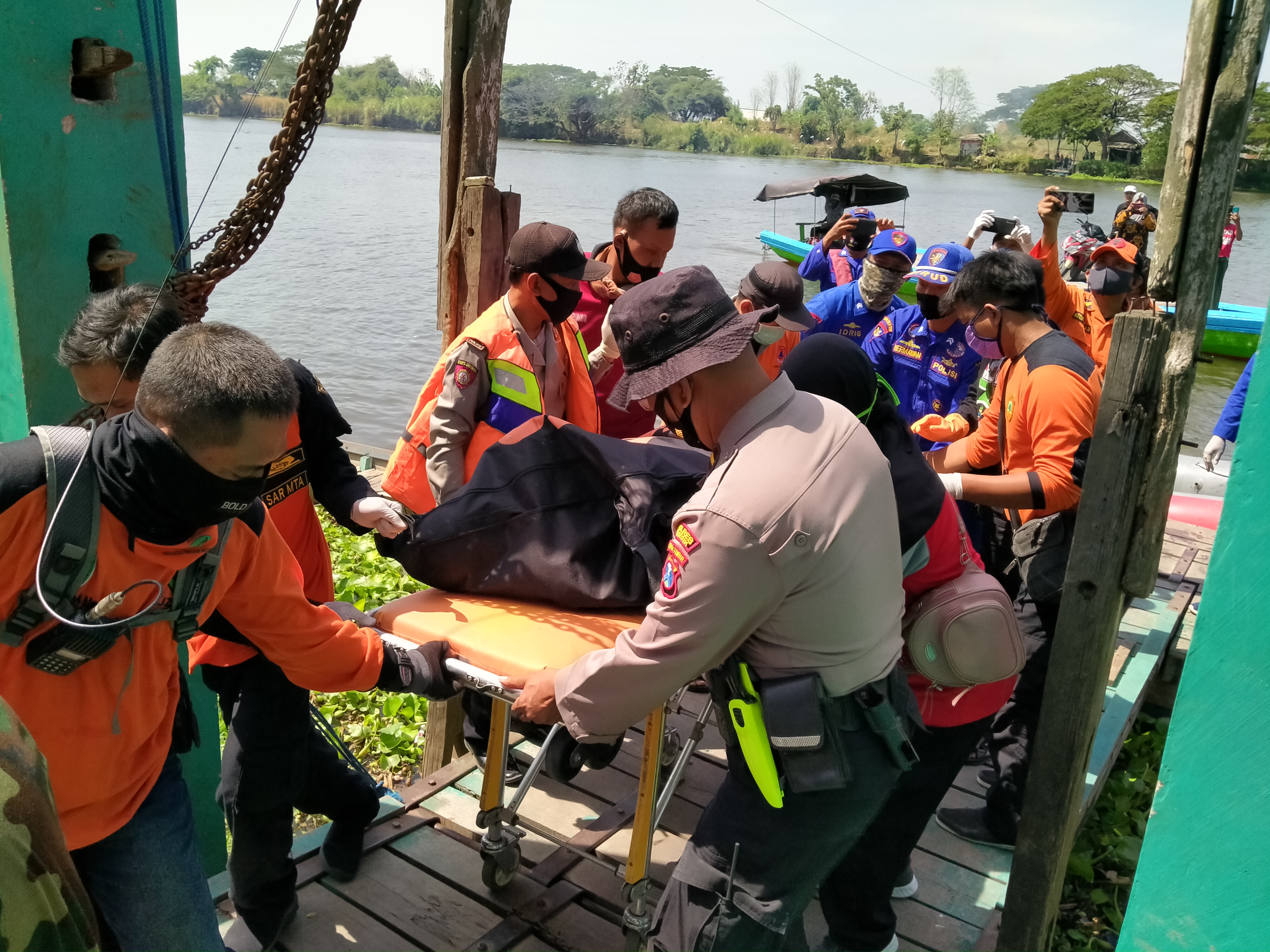 Petugas dari Polairut dan Basarnas saat mengevakuasi jasad korban bunuh diri ke mobil ambulan. (Foto: Azharil Farich/Ngopibareng.id)