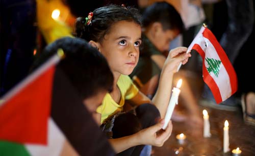 Warga Palestina termasuk anak-anak menyalakan lilin sebagai bentuk solidaritas untuk rakyat Lebanon yang berduka, di Rafah di Jalur Gaza Selatan, Palestina. (Foto:Ibraheem Abu Mustafa/Reuters)