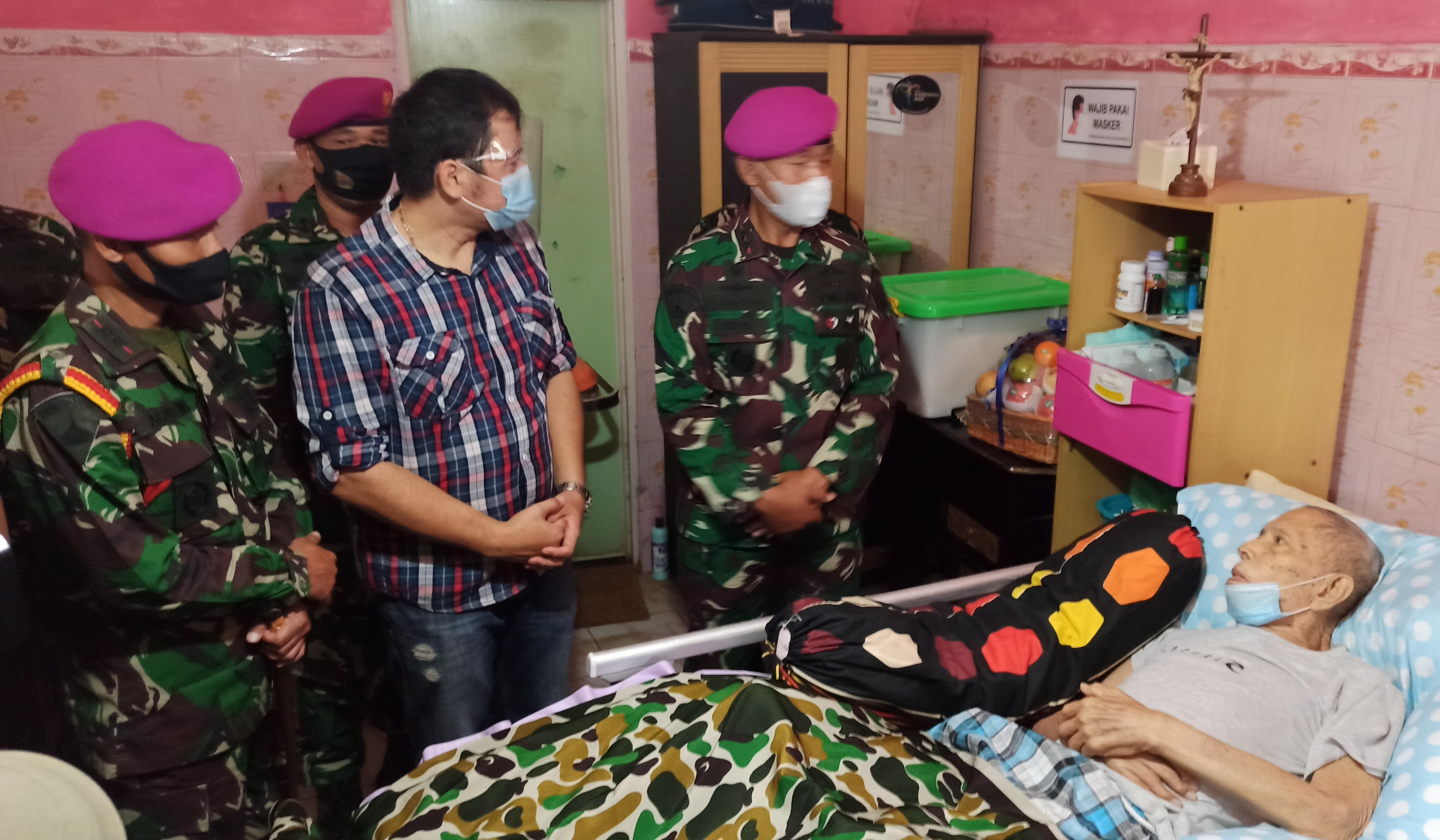 Dankormar Mayjend TNI (Mar) Suhartono (kanan) berbincang dengan Vence Kandou yang terbaring di tempat tidur. (Foto: Muh. Hujaini/Ngopibareng.id)