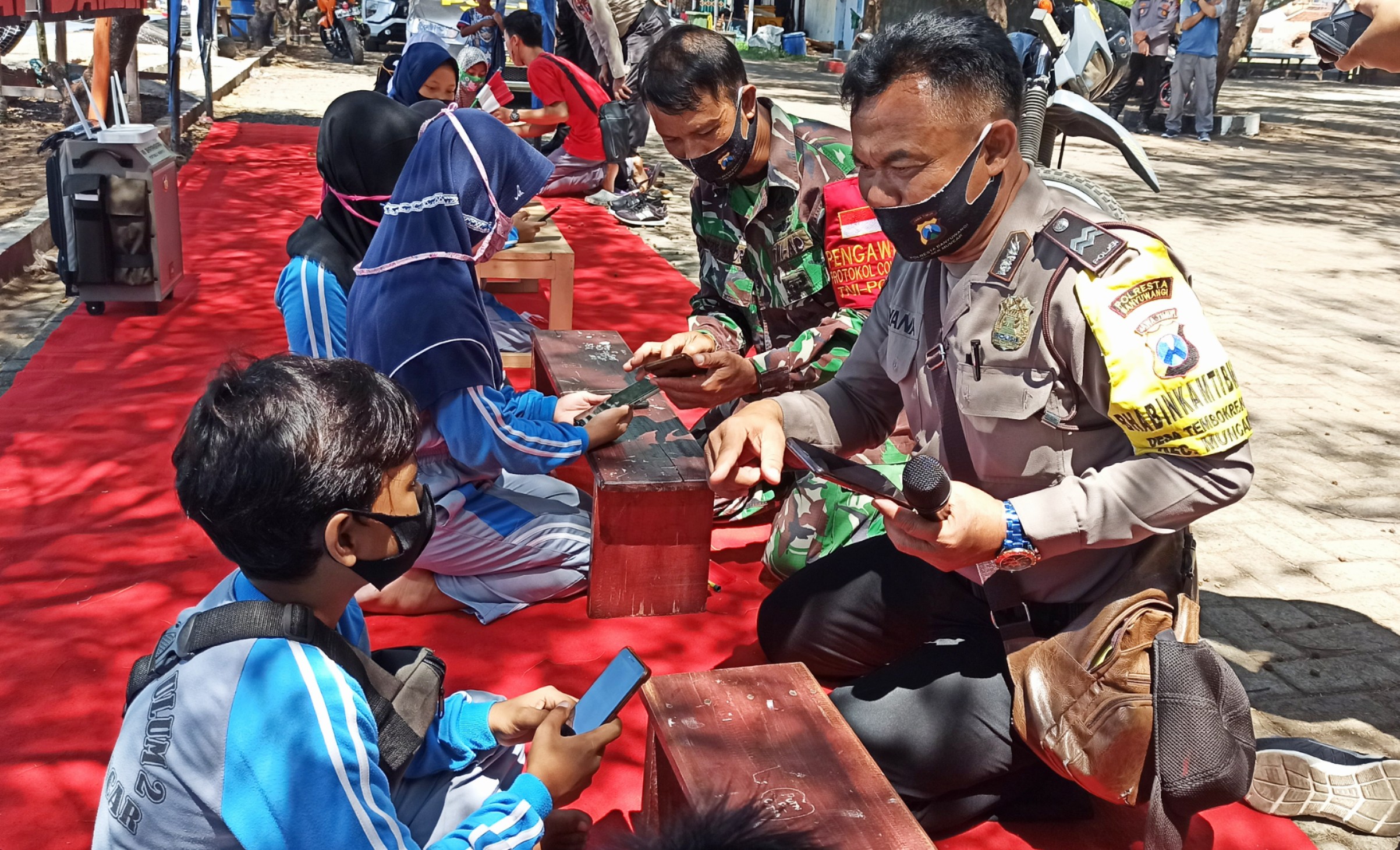 Bhabinkamtibmas dan Babinsa membimbing sejumlah anak-anak yang sedang belajar online menggunakan fasilitas internet dari WiFi Motor Bhabinkamtibmas (foto: Muh Hujaini/Ngopibareng.id)