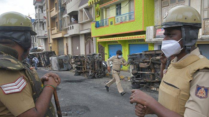 Petugas kepolisian berjaga di bekas lokasi kerusuhan di Kota Bangalore, India. (Foto: Manjunath Kiran/ AFP)