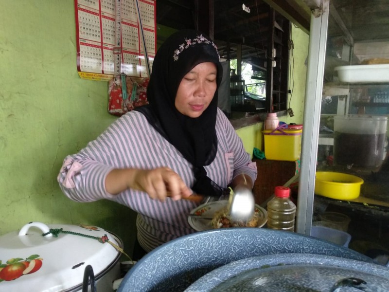 Asiyah saat melayani pembeli dengan menyiapkan seporsi lontong balap (Foto: M.Rizqi/Ngopibareng.id)