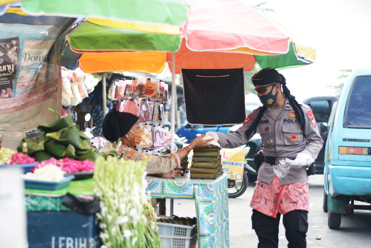 Personel Satbrimob Polda Jawa Timur (Jatim) ketika membagikan masker ke warga. (Foto: Alief Sambogo/Ngopibareng.id)