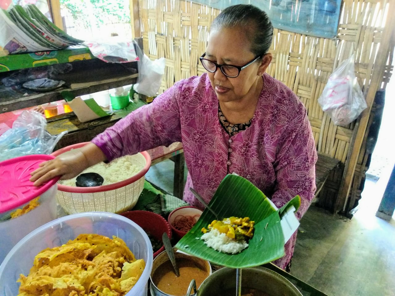 Supatmi saat menyipkan se porsi nasi lodeh untuk pembeli pada Sabtu, 22 Agustus 2020 pukul 07.00 WIB. Supatmi atau Mbah Mi tampak berhati-hati memegangi sepincuk nasi untuk pelanggan (Foto: M.Rizqi/Ngopibareng.id)
