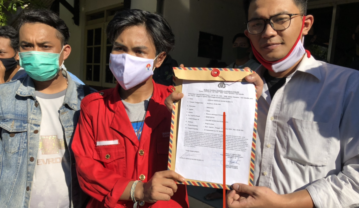 Ketua DPC GMNI Surabaya, Refi Achmad Zuhair (tengah), saat menunjukkan LP dari Polsek Sukolilo (Andhi Dwi/ Ngopibareng.id)