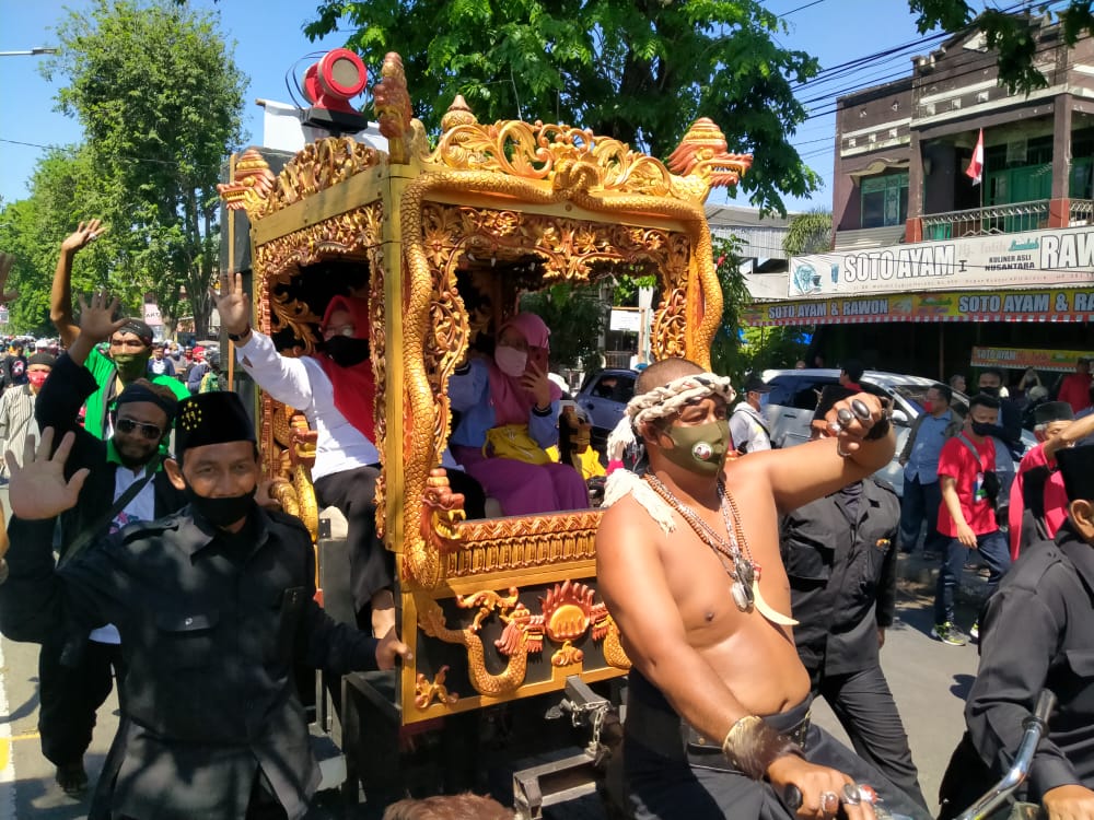 Bakal pasangan calon (bapaslon) Fandi Akhmad Yani dan Aminatun Habibah naik kereta kencana, saat mendaftar ke KPU Kabupaten Gresik, Jawa Timur, Jumat 4 September 2020. (Foto: Azharil Farich/Ngopibareng.id)