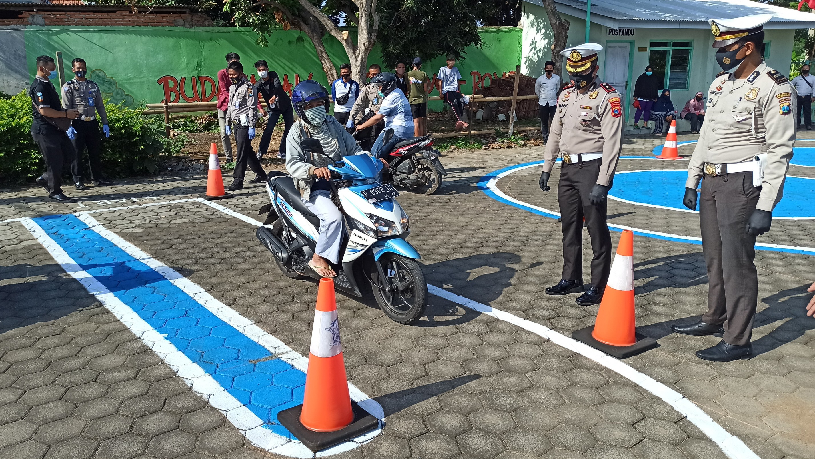 Warga berlatih ujian praktik SIM di lapangan Kampung Tangguh Klatak disaksikan Kasat Lantas Polresta Banyuwangi. (Foto: Muh Hujaini/Ngopibareng.id)