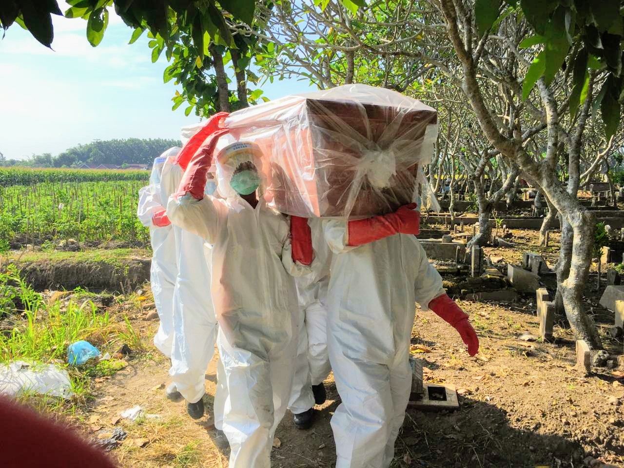 Saat petugas BPBD Jombang memikul peti jenazah di sebuah pemakaman di Jombang pada siang hari. (Foto: Dok. BPBD)