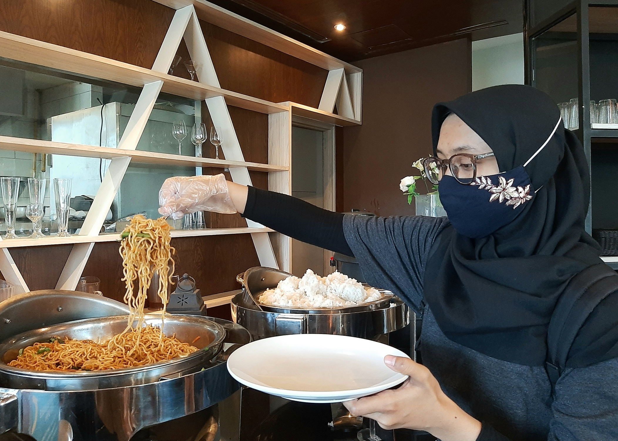 Salah satu protokol kesehatan yang diterapkan, yakni mengambil makanan sendiri dengan sarung tangan saat staycation di hotel. (Foto: Pita Sari/Ngopibareng.id)